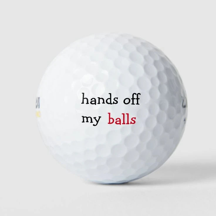White golf ball with a playful Hands off my balls text design